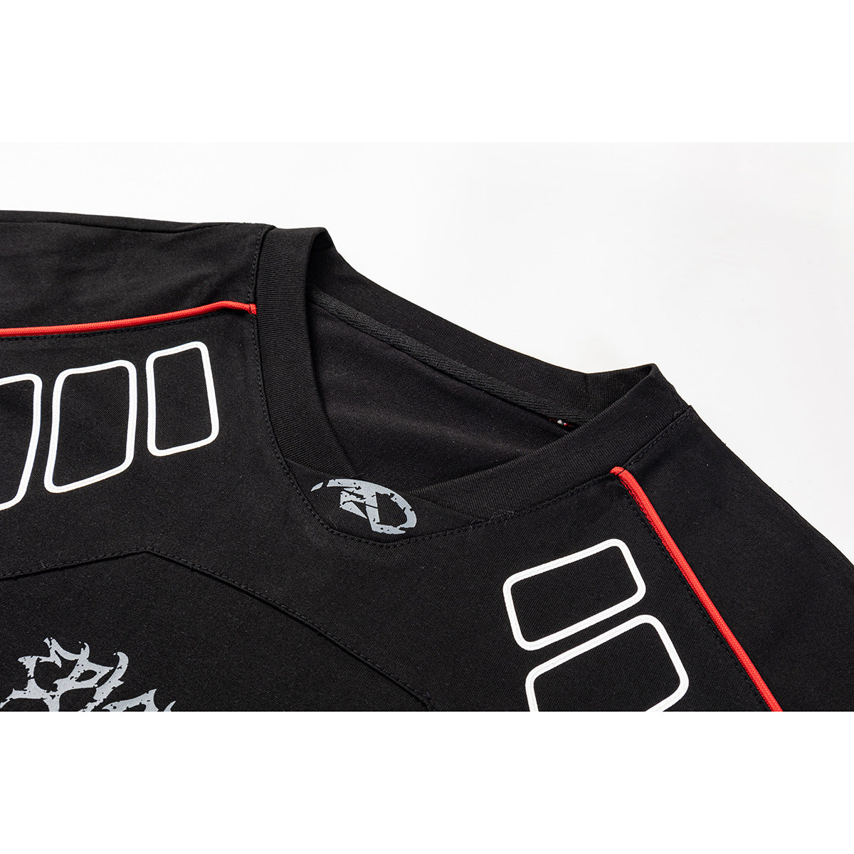 Close-up of a black shirt neckline and shoulder with red piping, white outlined graphics, and gray printed artwork.