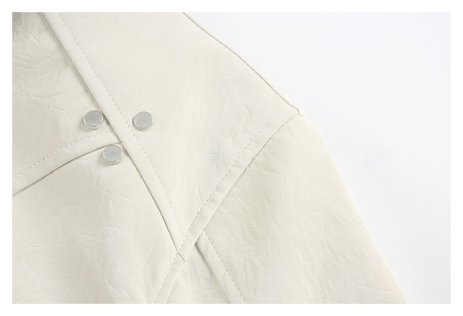 Close-up of an ivory jacket's overlapping front panels with three round silver snaps and stitched seams.