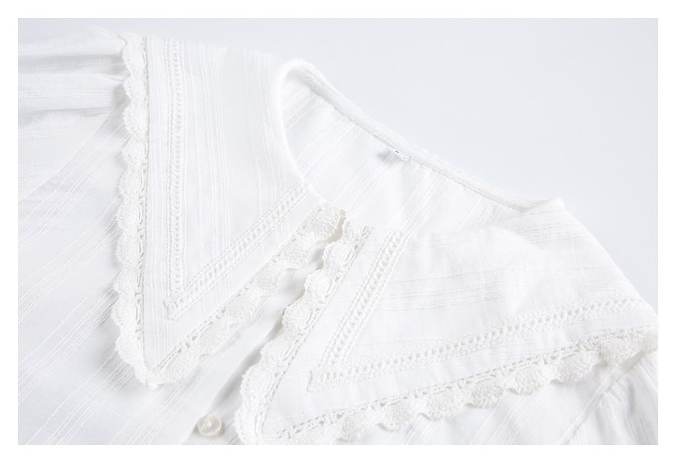 Close-up of a white shirt's wide pointed collar with lace trim and stitched stripe details.