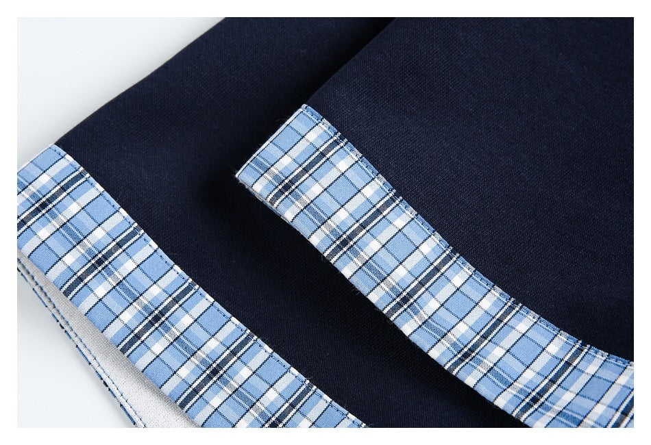 Close-up of blue plaid trim against navy polo fabric, showing the collar edge and stitching.