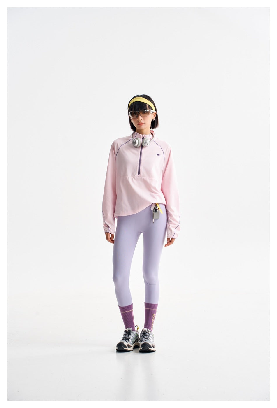 Front view of a model wearing a pale pink quarter-zip top and pale lavender leggings.