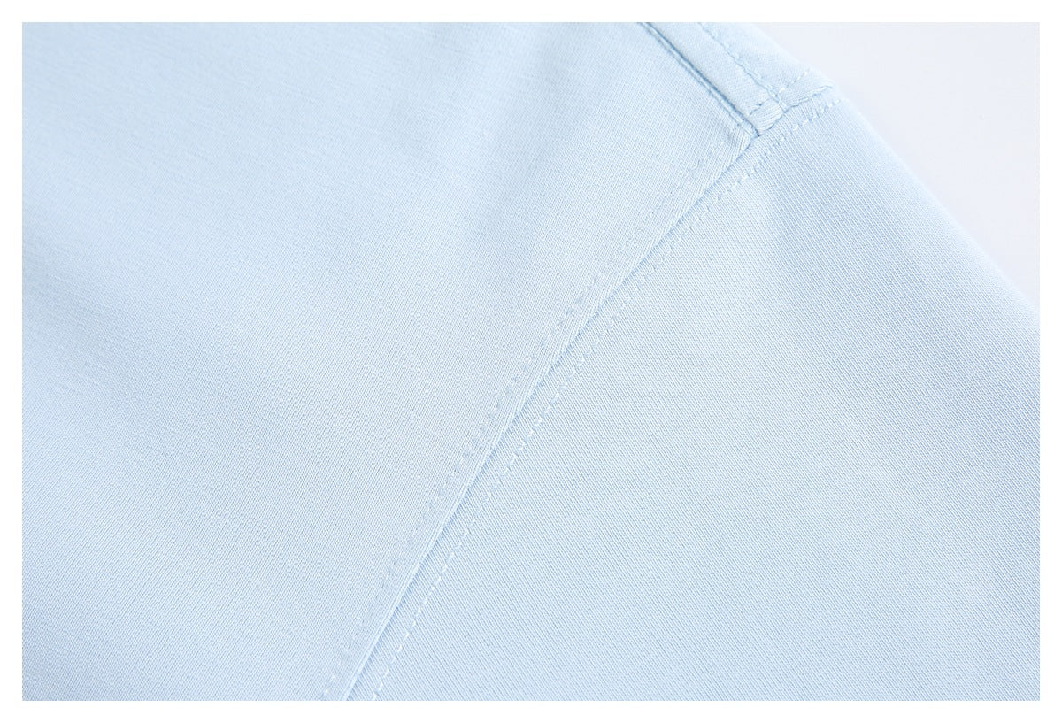 Close-up of light blue garment fabric with a curved stitched seam.