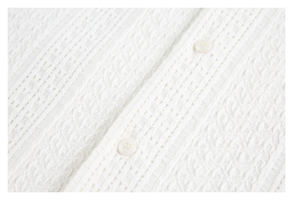 White textured knit garment close-up showing two buttons on a patterned placket.