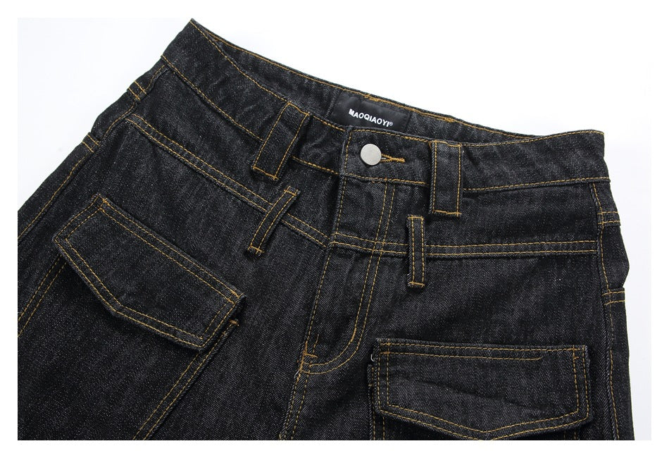 Close-up of the front waistband and pockets of black jeans with golden contrast stitching.