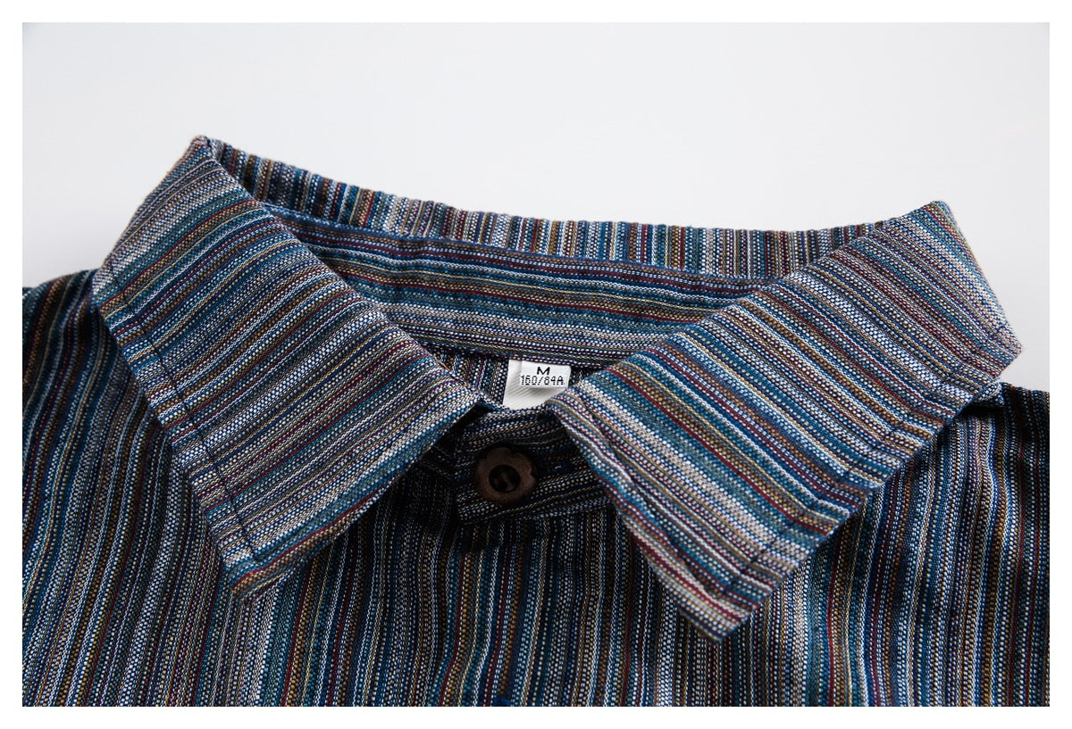 Close-up of a pointed collar and brown button on a dark blue multicolor-striped shirt.