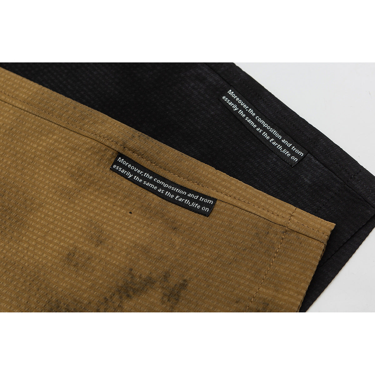 Close-up of ochre-brown and black shorts with small black sewn-in labels bearing white English text.