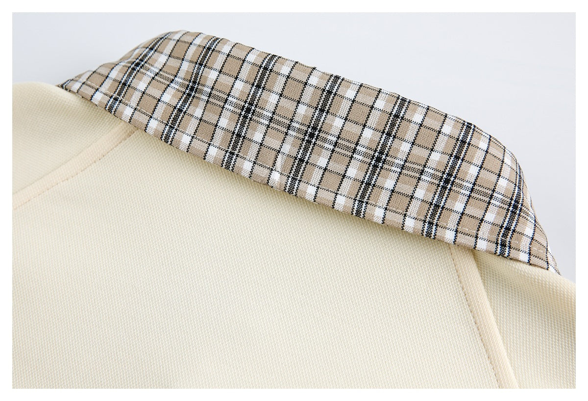 Close-up of a cream garment's beige, black, and white plaid collar.