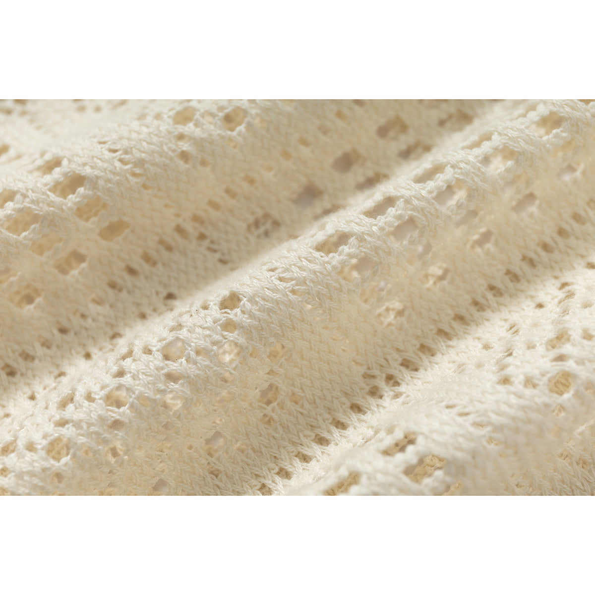 Macro view of the ivory shirt’s textured openwork pattern.