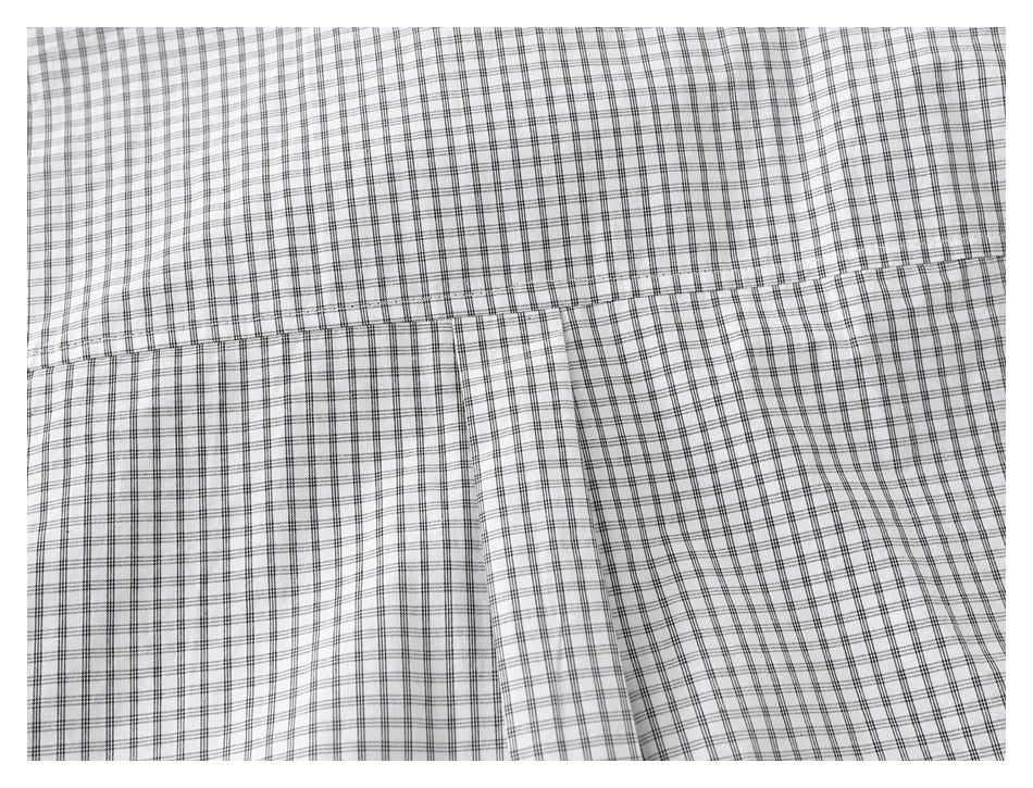 Close-up of a horizontal yoke seam and center pleat on the black grid-check shirt.