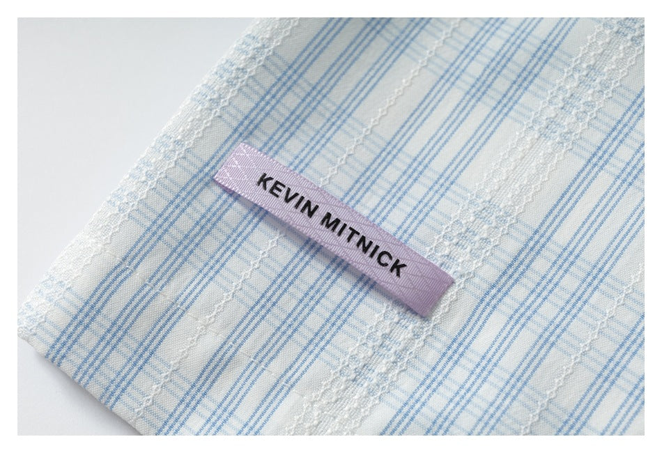 Close-up of a purple KEVIN MITNICK label on white and blue plaid fabric with textured stripes.