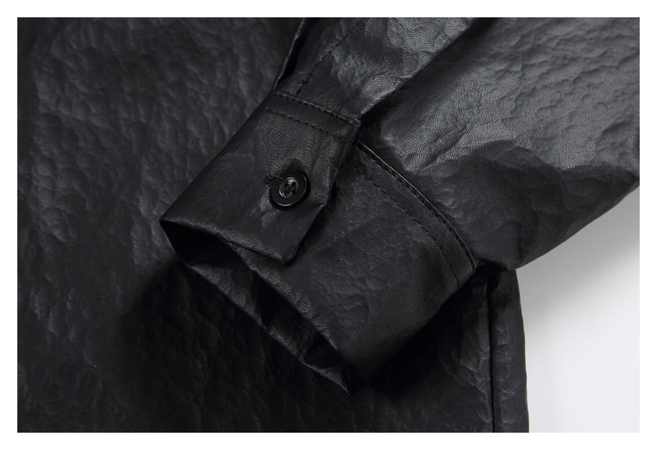 Close-up of a black textured jacket sleeve cuff with a button and stitched seam.
