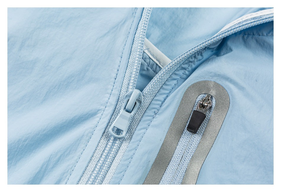 Close-up of a light blue jacket showing its main zipper and gray-trimmed zip pocket.