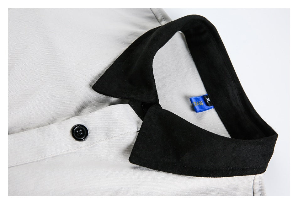 Close-up of a black shirt collar, blue size tag, and black button on white fabric.