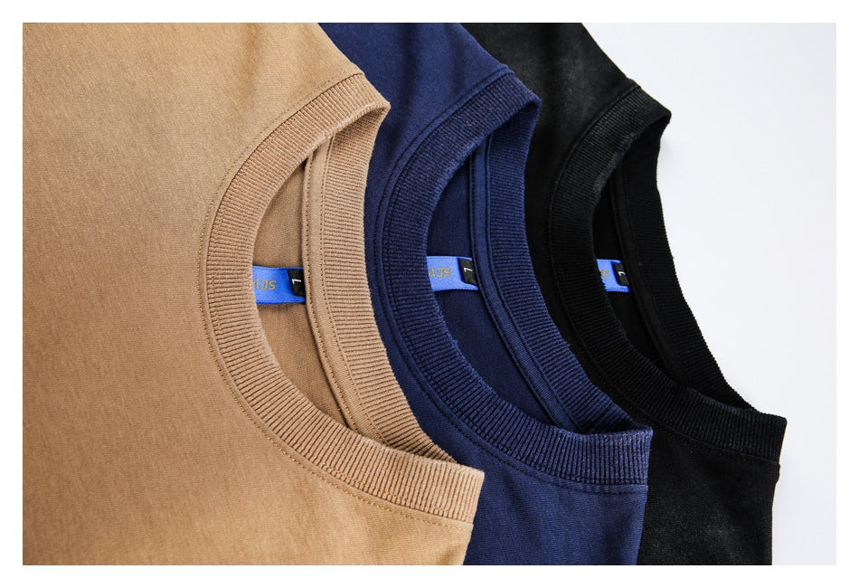 Close-up of crew necklines on camel-brown, navy, and black T-shirts arranged together.