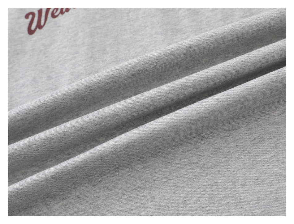 Close-up of the heather gray T-shirt fabric draped in folds, with part of its burgundy print visible.