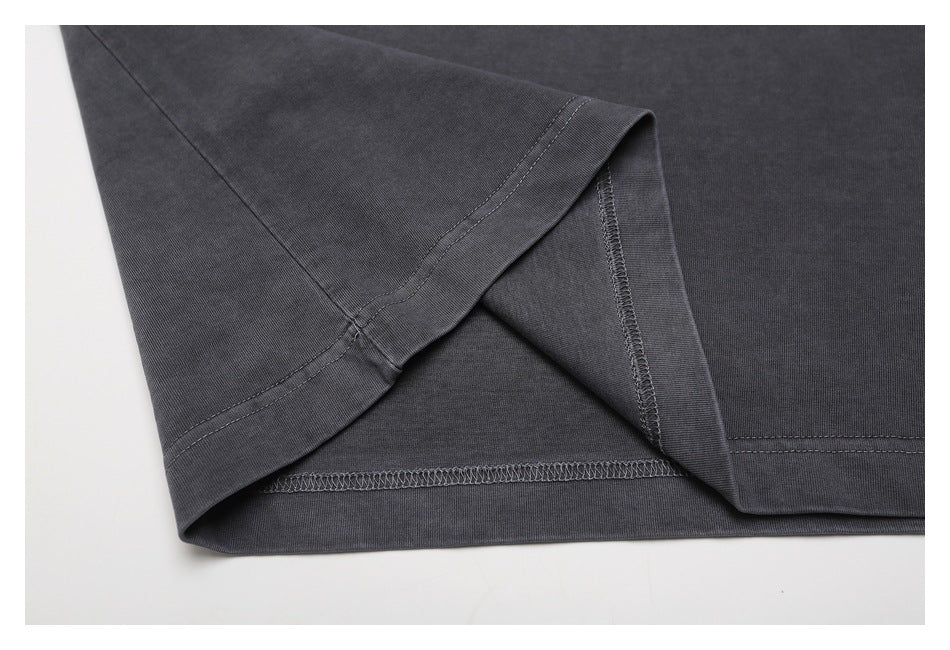 Close-up of the charcoal T-shirt's sleeve and side seam, showing the hem and overlock stitching.