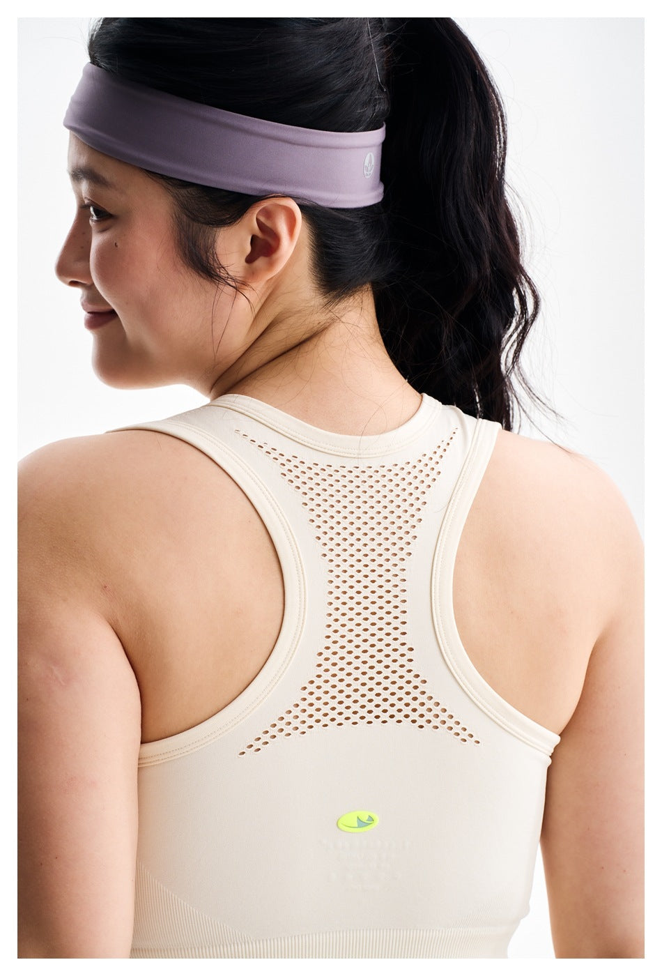 Back close-up of an ivory racerback crop top with a perforated mesh panel, worn with a lavender headband.
