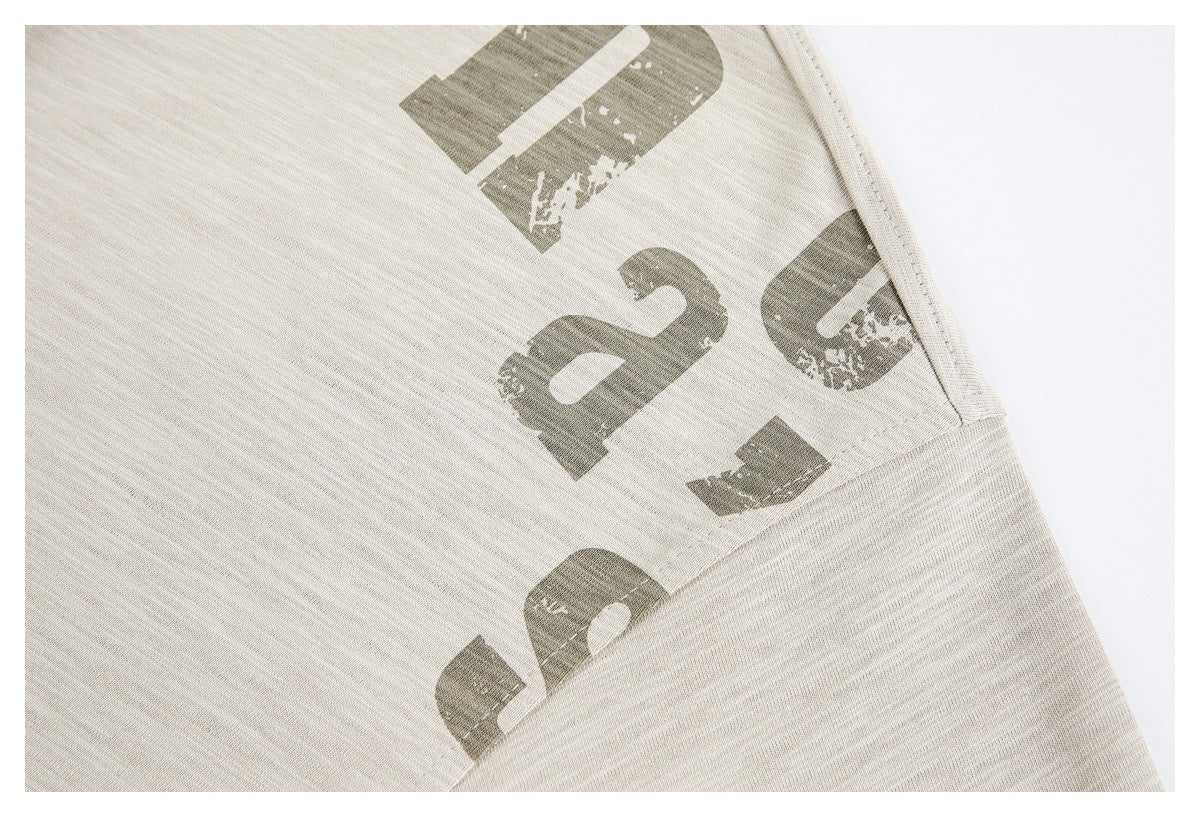 Close-up of a cream shirt’s side seam and distressed olive lettering.