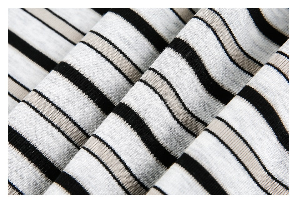 Close-up of white knit fabric with bold black stripes and thin paired lines, arranged in folds.