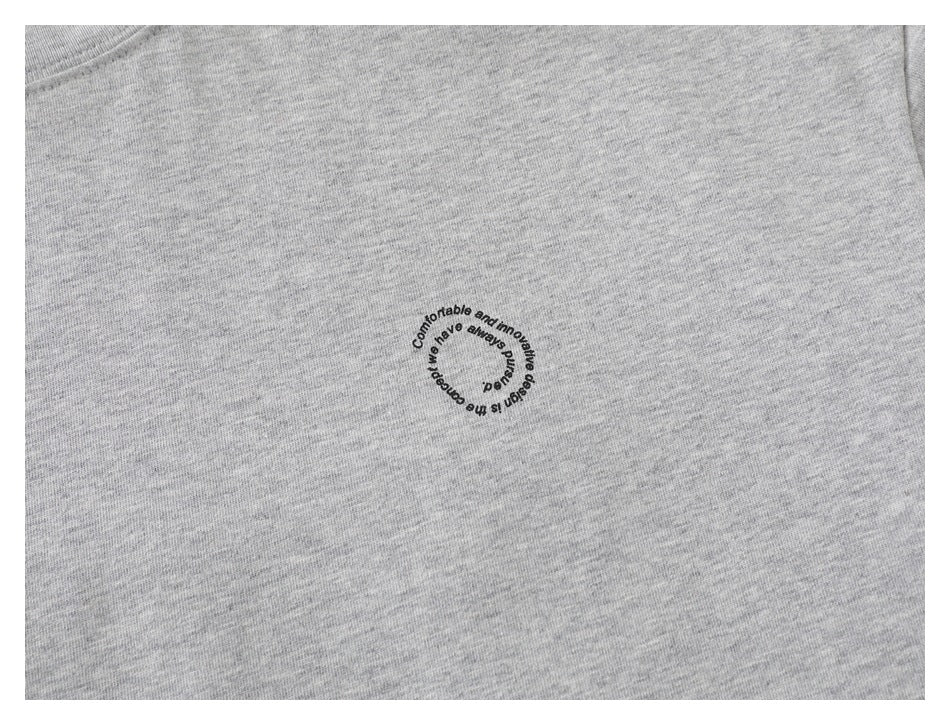 Close-up of a small circular English text print on heather gray T-shirt fabric.