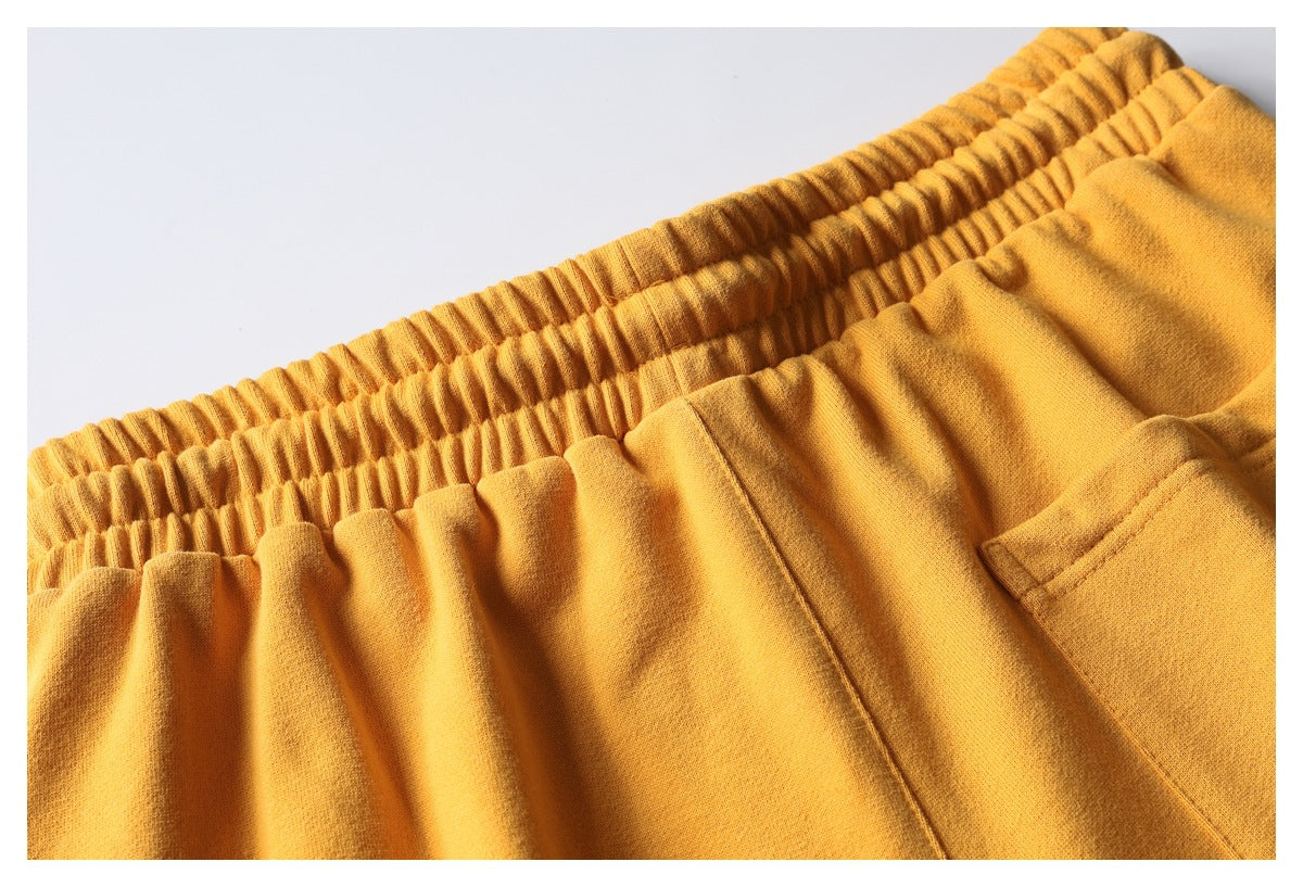 Close-up of mustard pants showing a gathered elastic waistband and a side pocket.