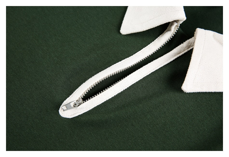 Close-up of the partially open metal zipper and white placket on a dark green top.