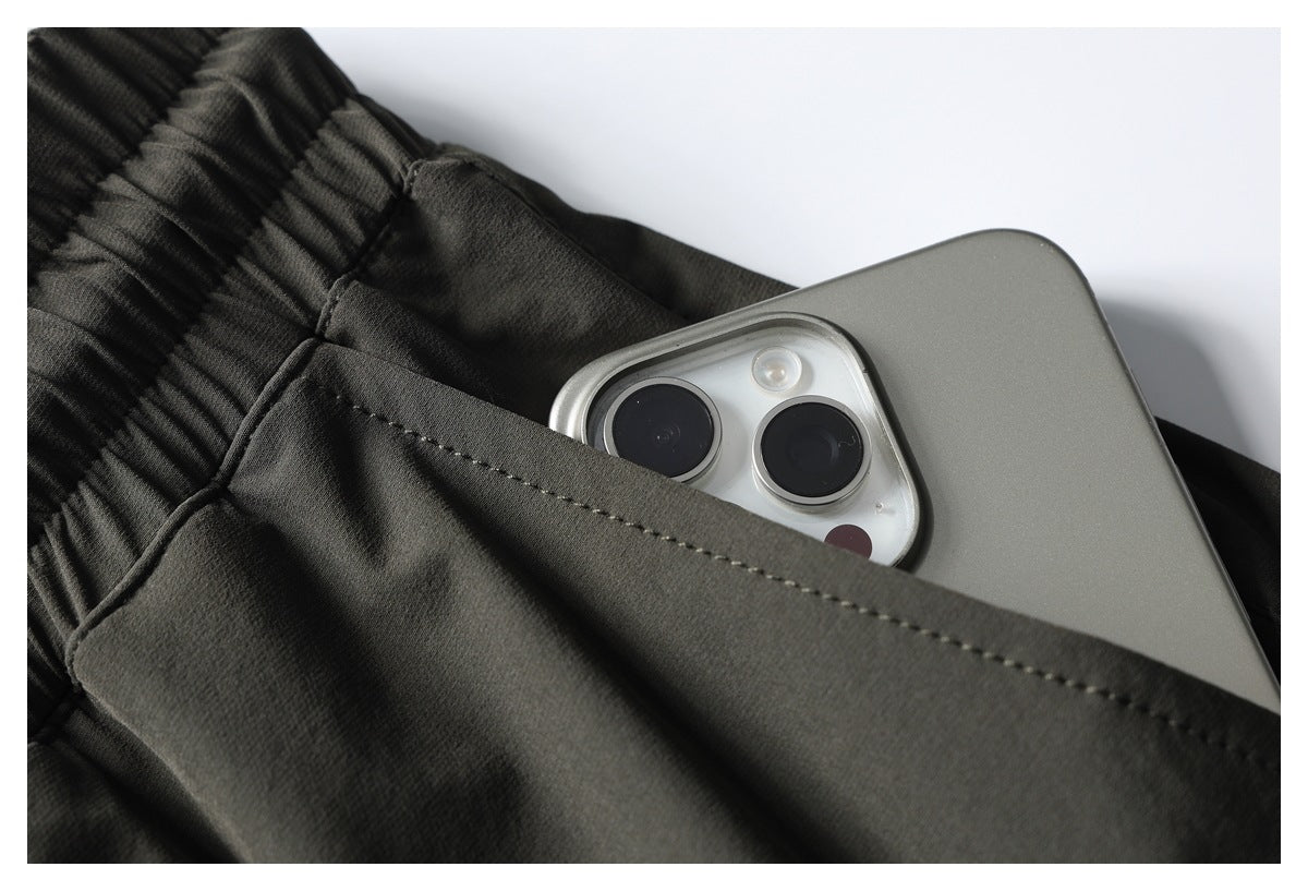 Close-up of a rear pocket on dark olive pants holding a smartphone.