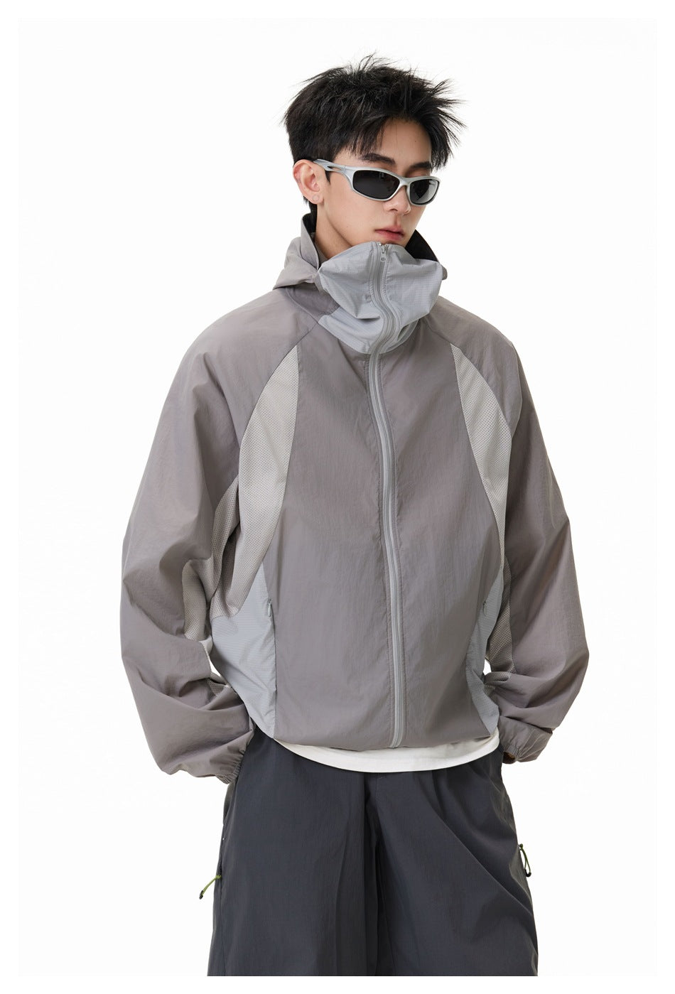 Model wearing a gray zip jacket with a high collar and pale mesh side panels, shown from the front.