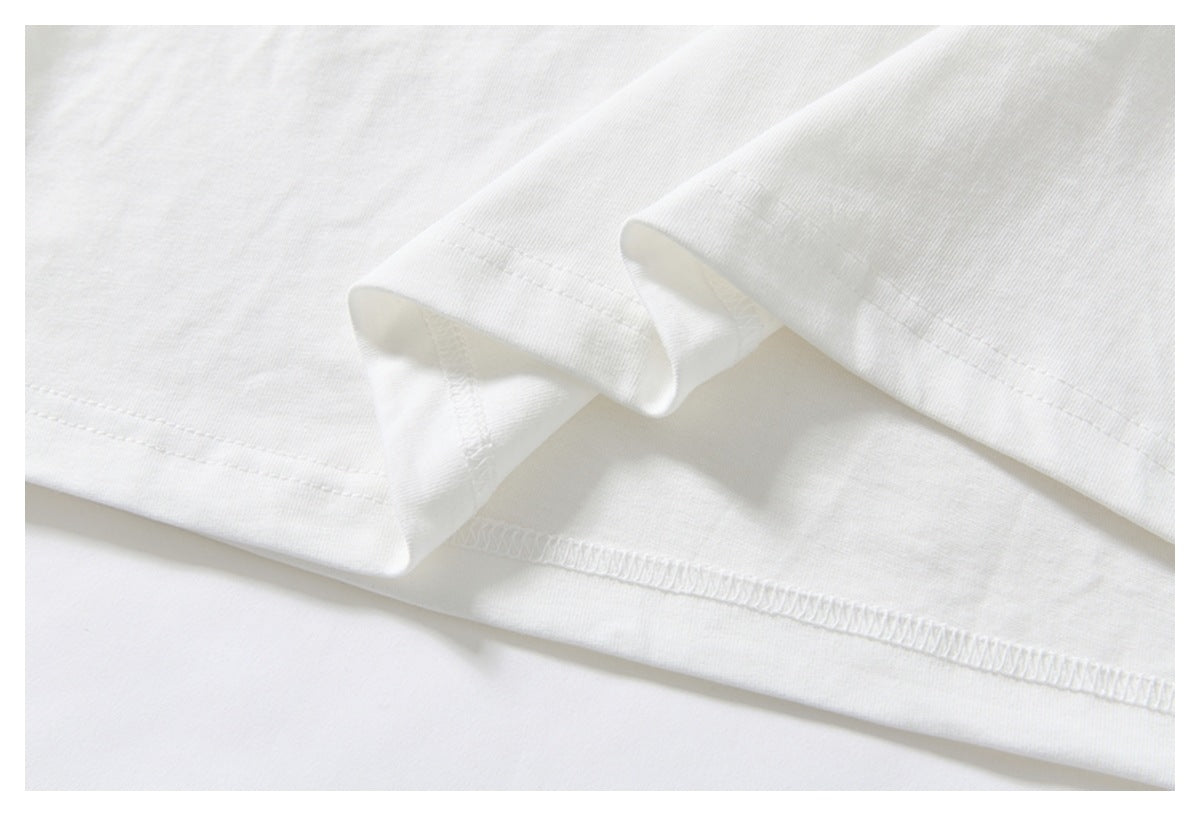 Close-up of the white shirt's folded hem and neat stitching on a pale background.