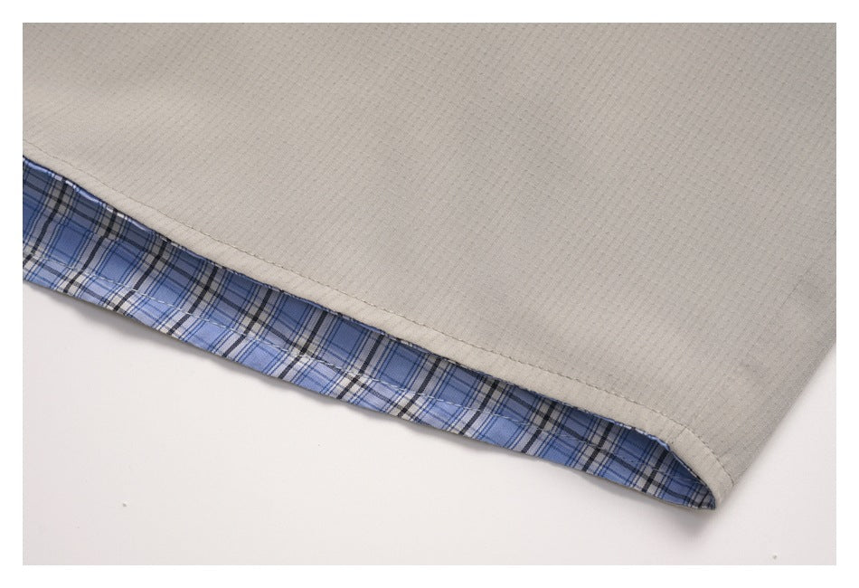 Close-up of a light taupe garment hem showing blue plaid lining inside the edge.