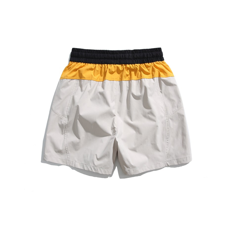Back view of light gray shorts with a mustard-yellow band and black elastic waistband.