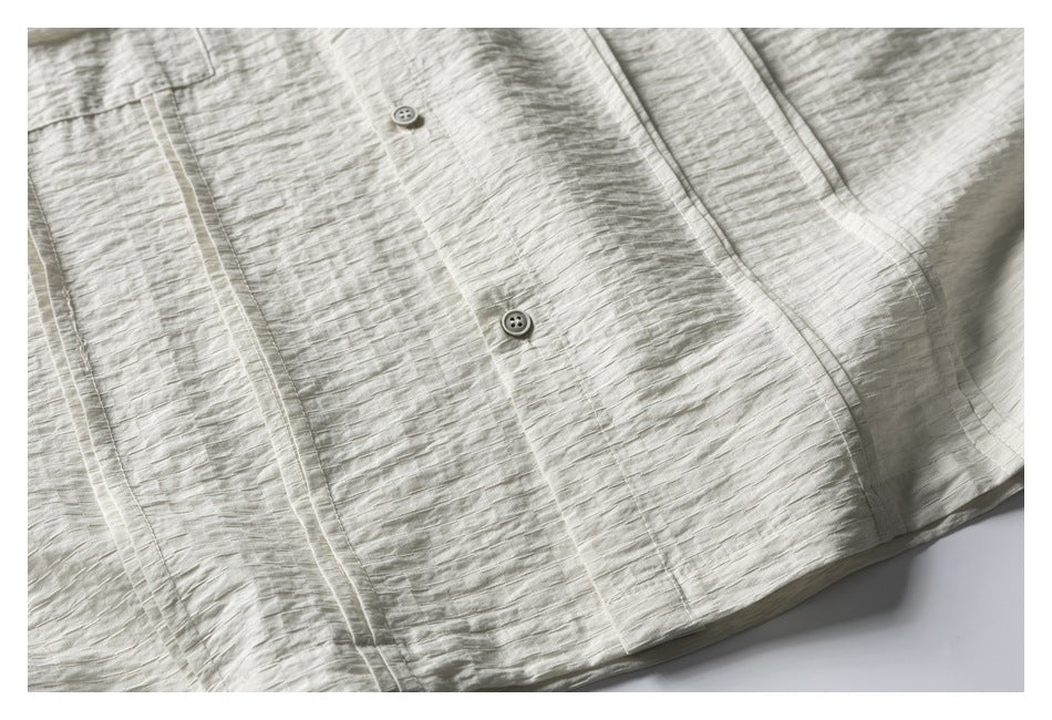 Pale ivory textured garment front with two small buttons and stitched panel seams.