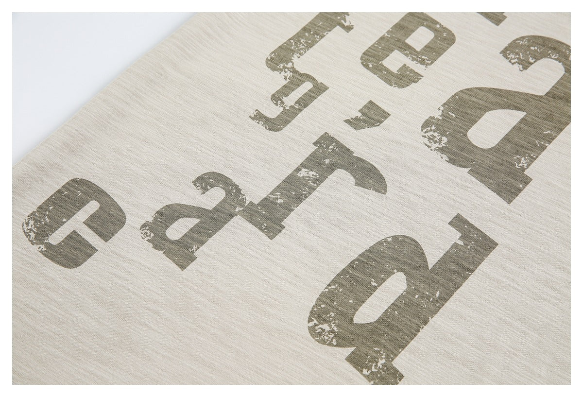Close-up of distressed dark lettering printed on beige heathered fabric.