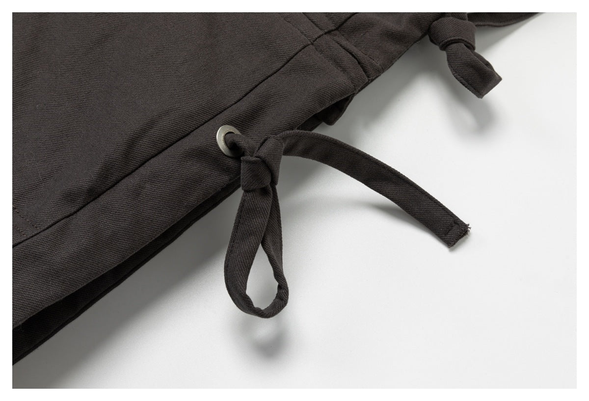 Close-up of a charcoal garment's drawstring threaded through a metal eyelet.