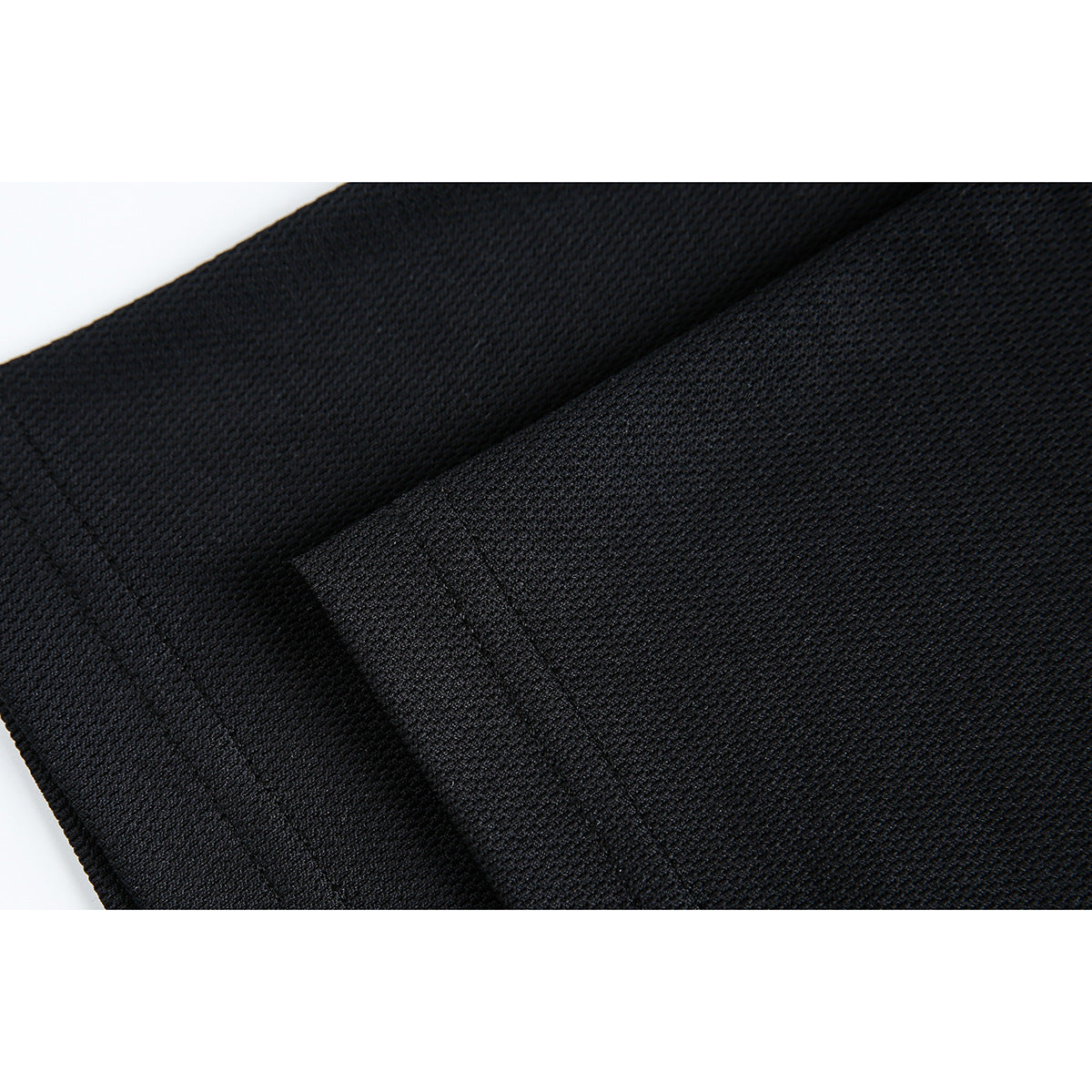 Close-up of black garment fabric showing its small textured knit surface and folded edge.