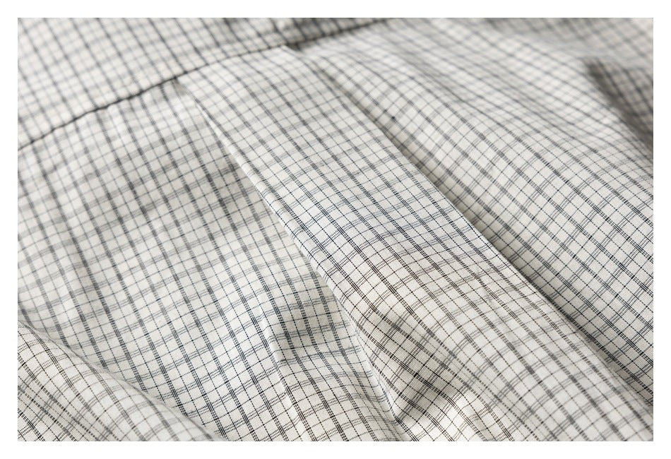 Close-up of checked fabric folds and stitching on a cream garment.