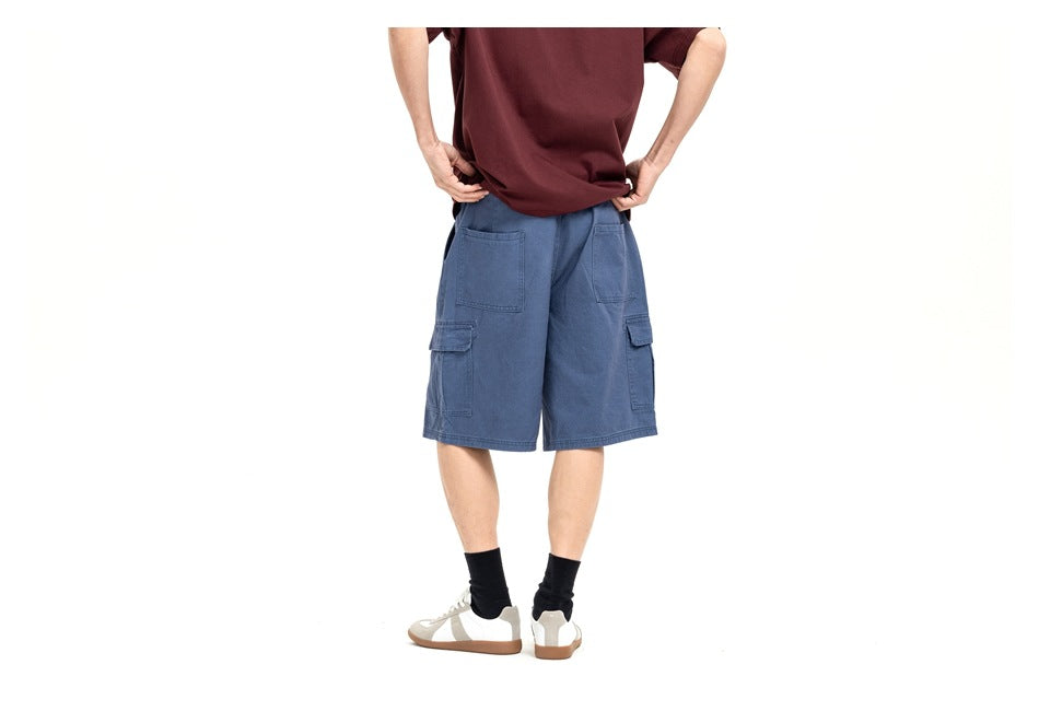 Rear view of a model wearing blue cargo shorts with flap pockets and a burgundy T-shirt.