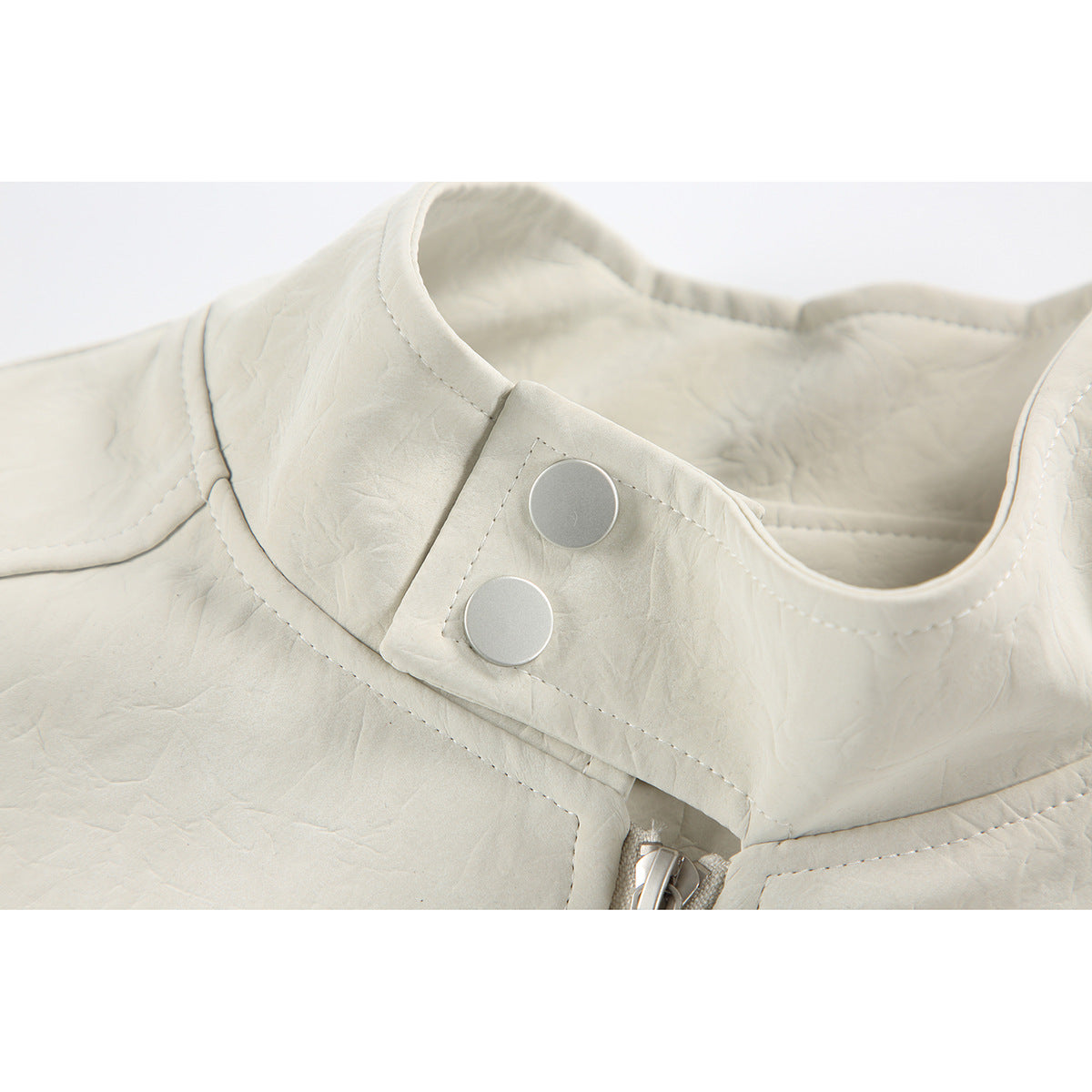 Close-up of an ivory jacket's stand collar, snap-button tab, stitching and zipper.