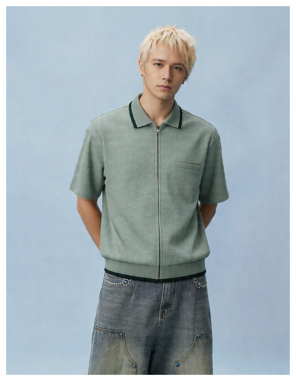 Model wearing the light green zip-front short-sleeve knit shirt with dark collar trim and gray jeans, facing front