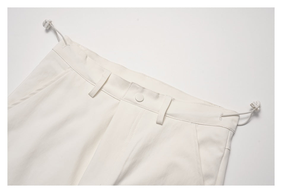 Close-up of the ivory pants waistband, button, belt loops, and side drawcords.