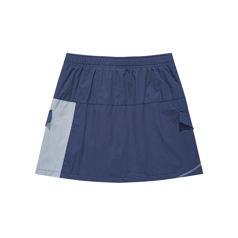 Front view of a navy A-line skirt with a light gray side panel, elastic waistband, and cargo-style pocket flaps.