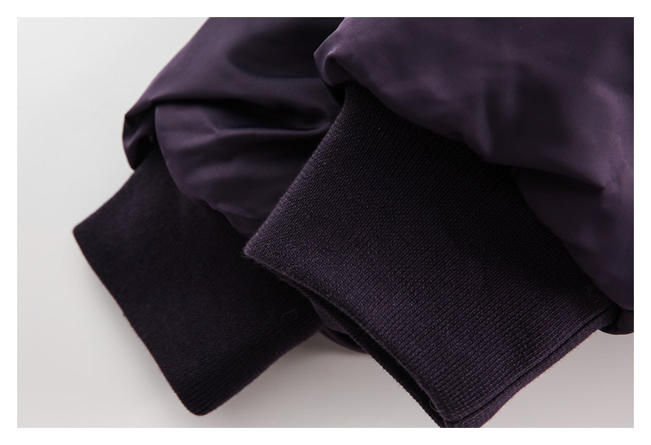 Close-up of a dark purple jacket sleeve ending in a wide dark ribbed cuff.