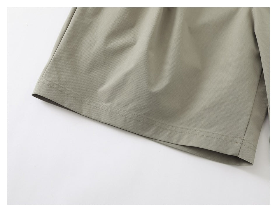 Close-up of the stitched hem on a light khaki shorts leg.