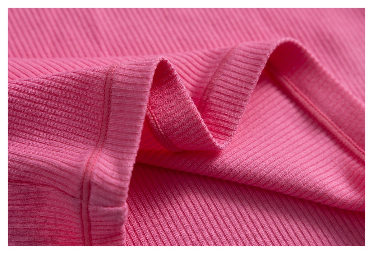 Close-up of pink ribbed fabric showing folded edges, stitching, and the garment's texture.