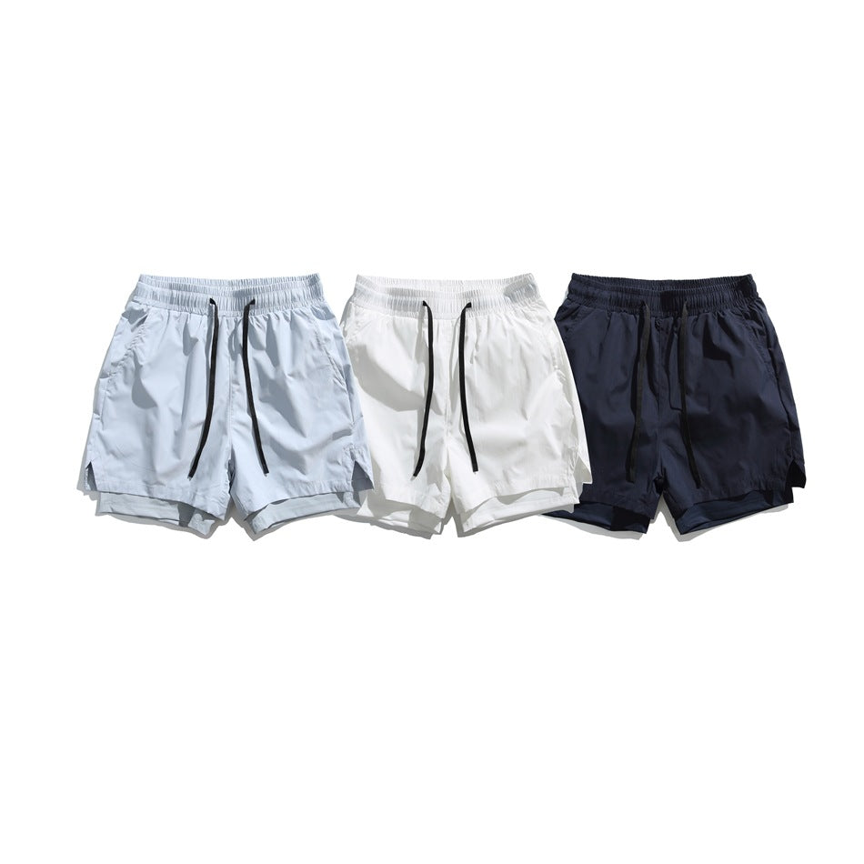 Three pairs of elastic-waist shorts with black drawstrings in pale blue-gray, white, and navy.