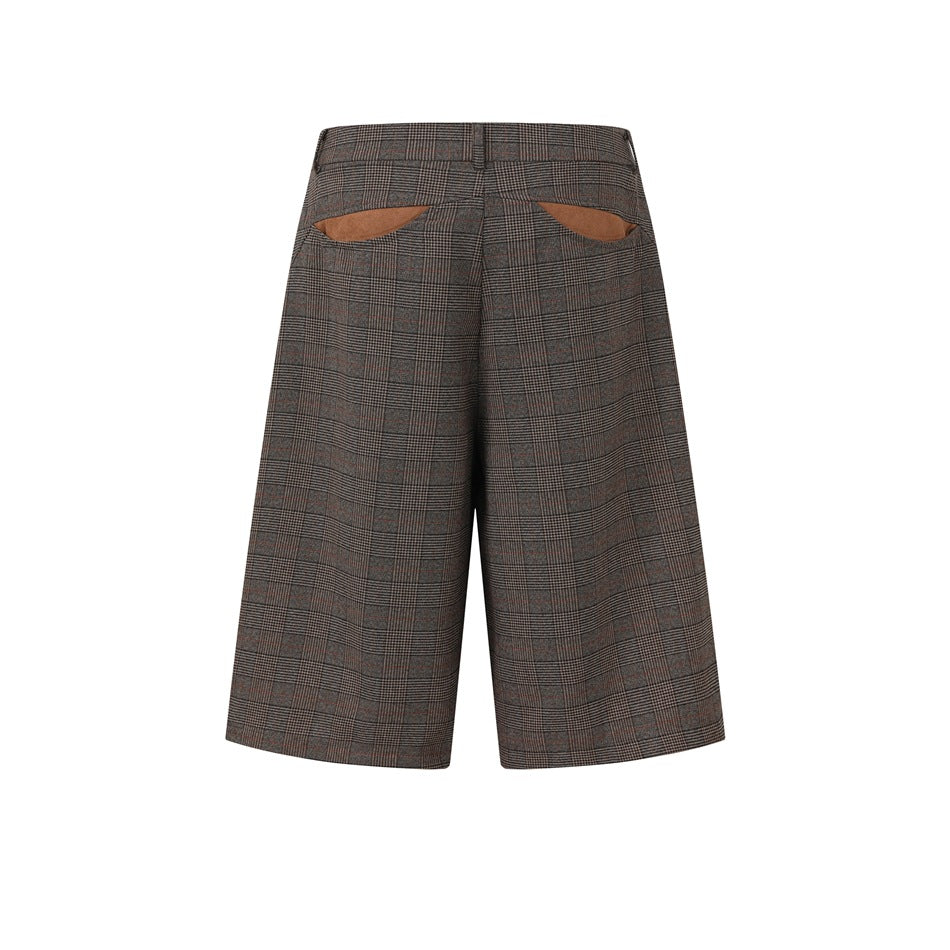 Rear view of brown plaid wide-leg shorts with curved back pocket openings and tan pocket lining.