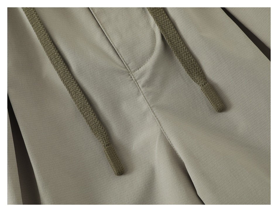 Close-up of olive braided drawstrings against light khaki shorts.