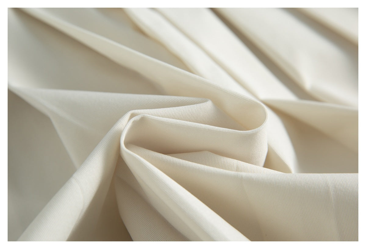 Close-up of softly folded ivory fabric showing its fine ribbed texture.