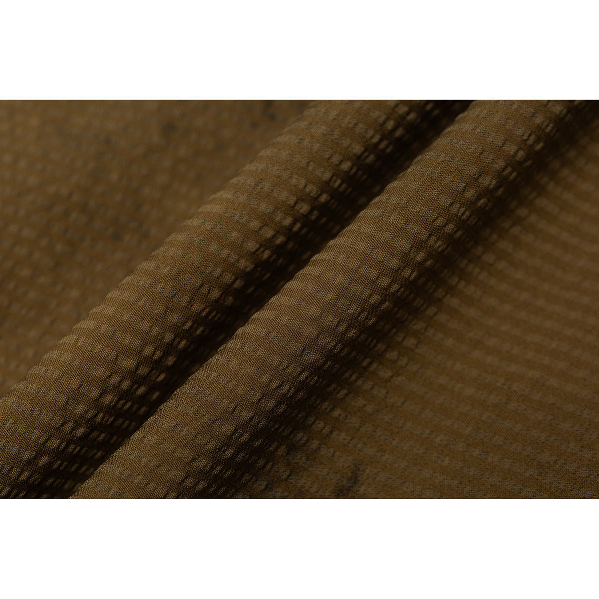 Macro view of textured ochre-brown shorts fabric folded to show its surface and stitching.