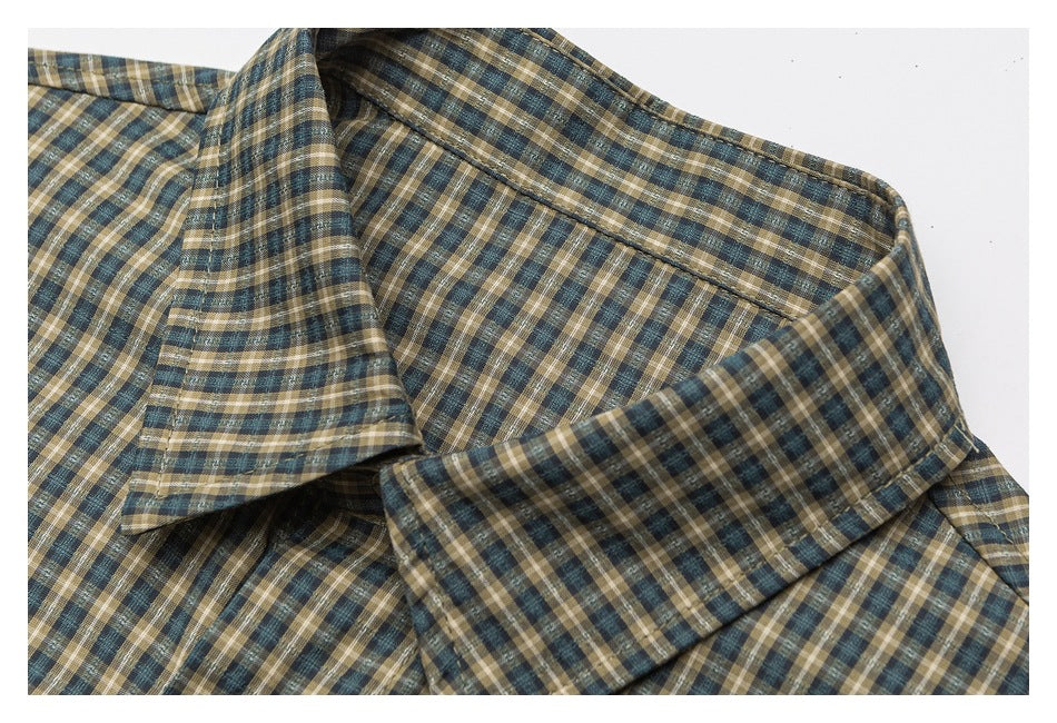 Close-up of a pointed collar on a blue, tan, and cream plaid shirt.